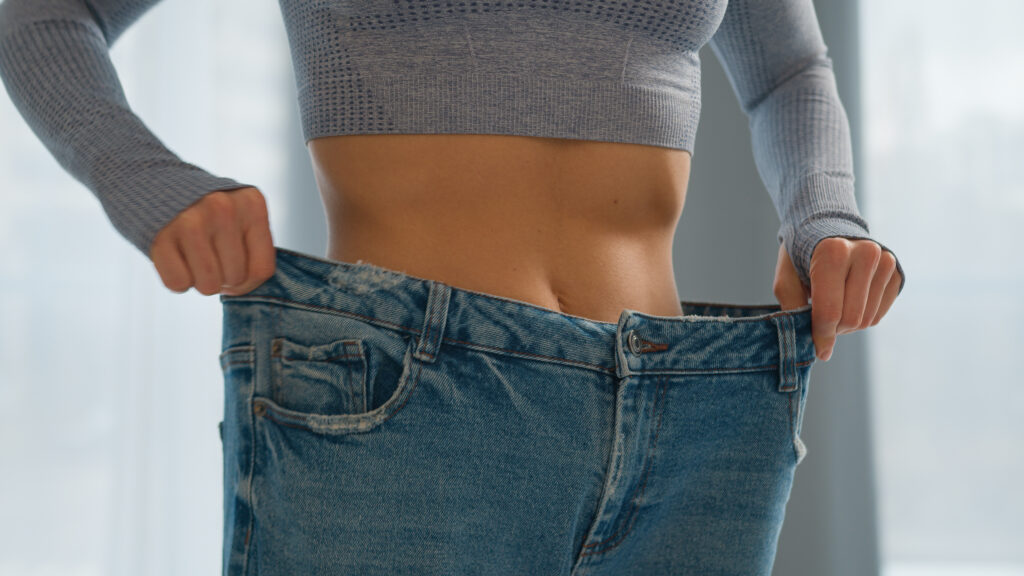 Mental health after bariatric surgery - woman measuring slim waist showing positive body image transformation